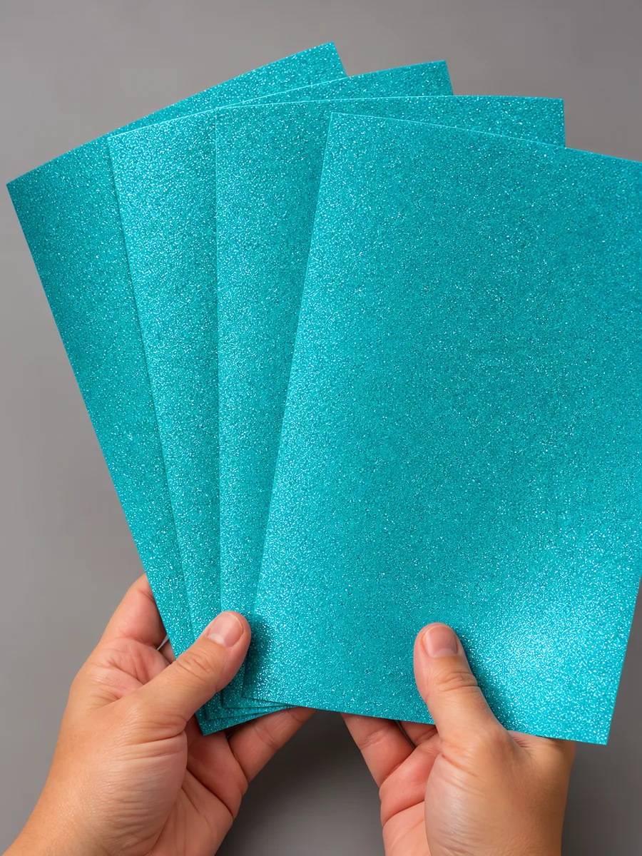 Manos sosteniendo varias hojas de papel con glitter cielo magico abiertas en abanico