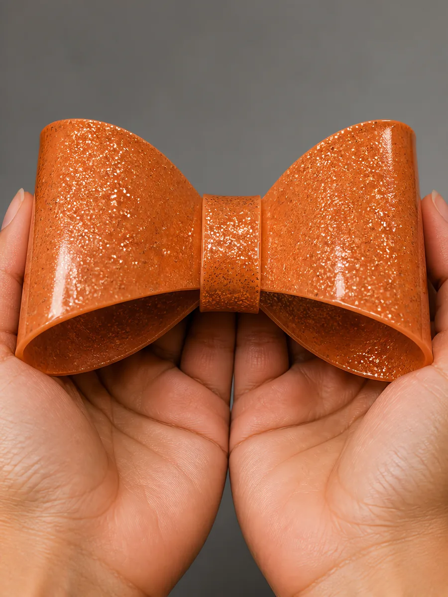 Manos sosteniendo un moño de papel bronce con glitter