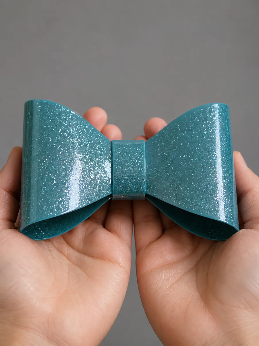 Manos sosteniendo un moño de papel celeste lluvia con glitter