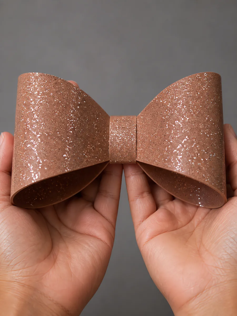 Manos sosteniendo un moño de papel dorado nocturno con glitter