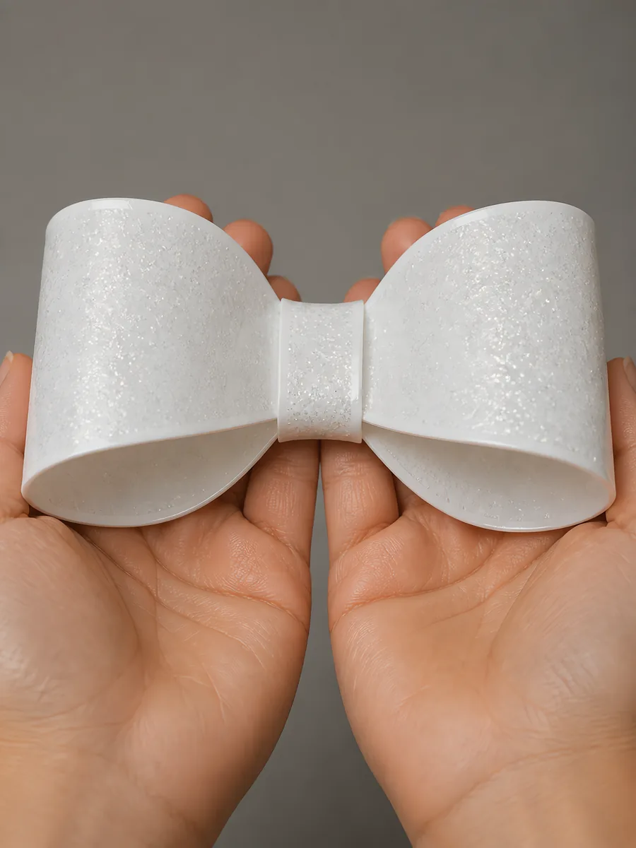 Manos sosteniendo un moño de papel plata lunar con glitter