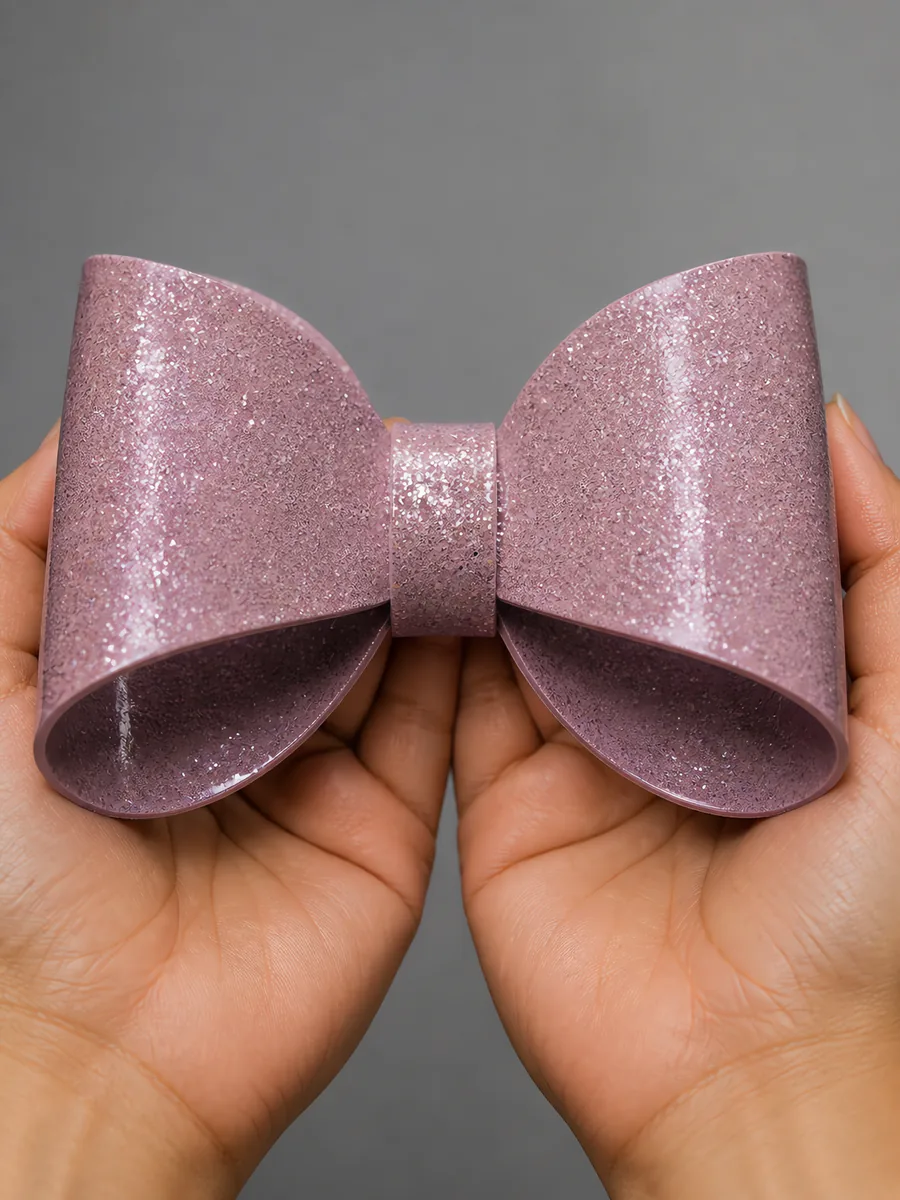 Manos sosteniendo un moño de papel rosa flamenco con glitter