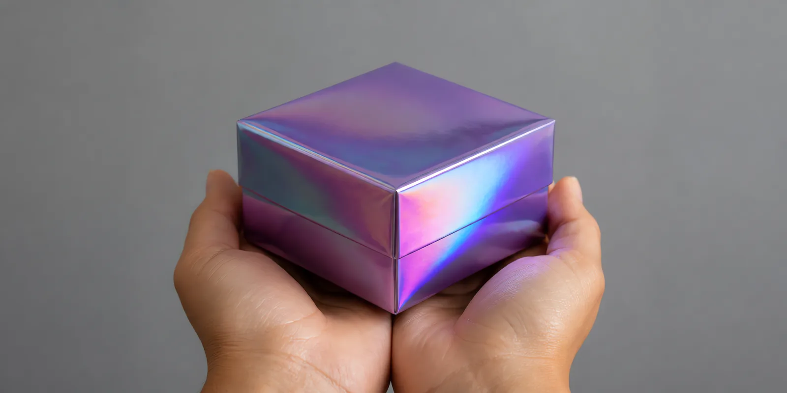 Manos sosteniendo una cajita armada con una hoja de Metalina en el acabado morado brillante