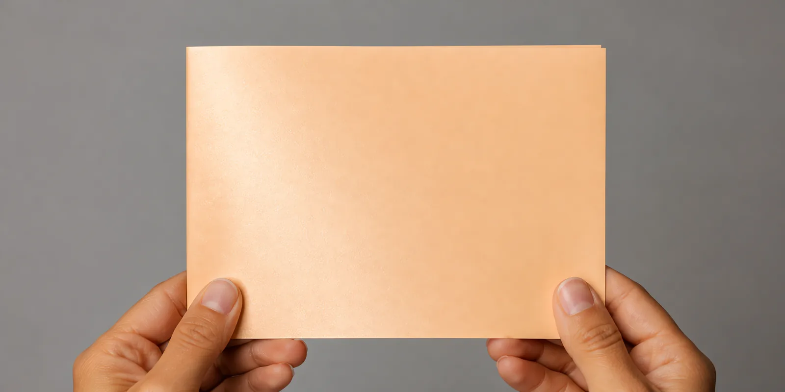 Manos sosteniendo una tarjeta doblada en papel perlado bronce