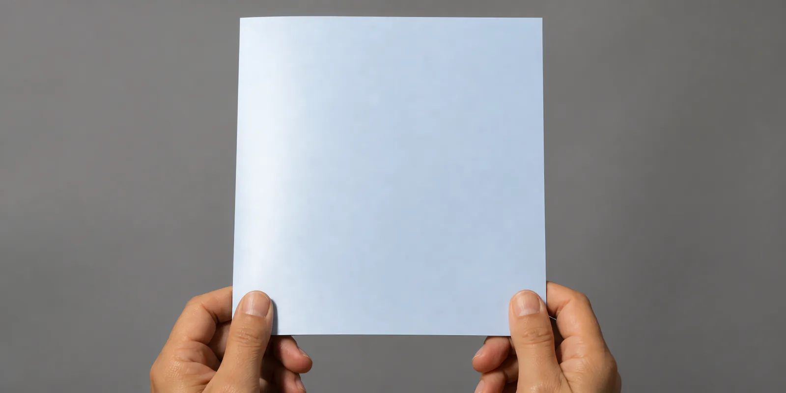 Manos sosteniendo una tarjeta doblada en papel perlado gris