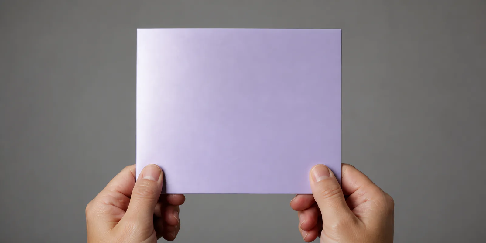 Manos sosteniendo una tarjeta doblada en papel perlado violeta