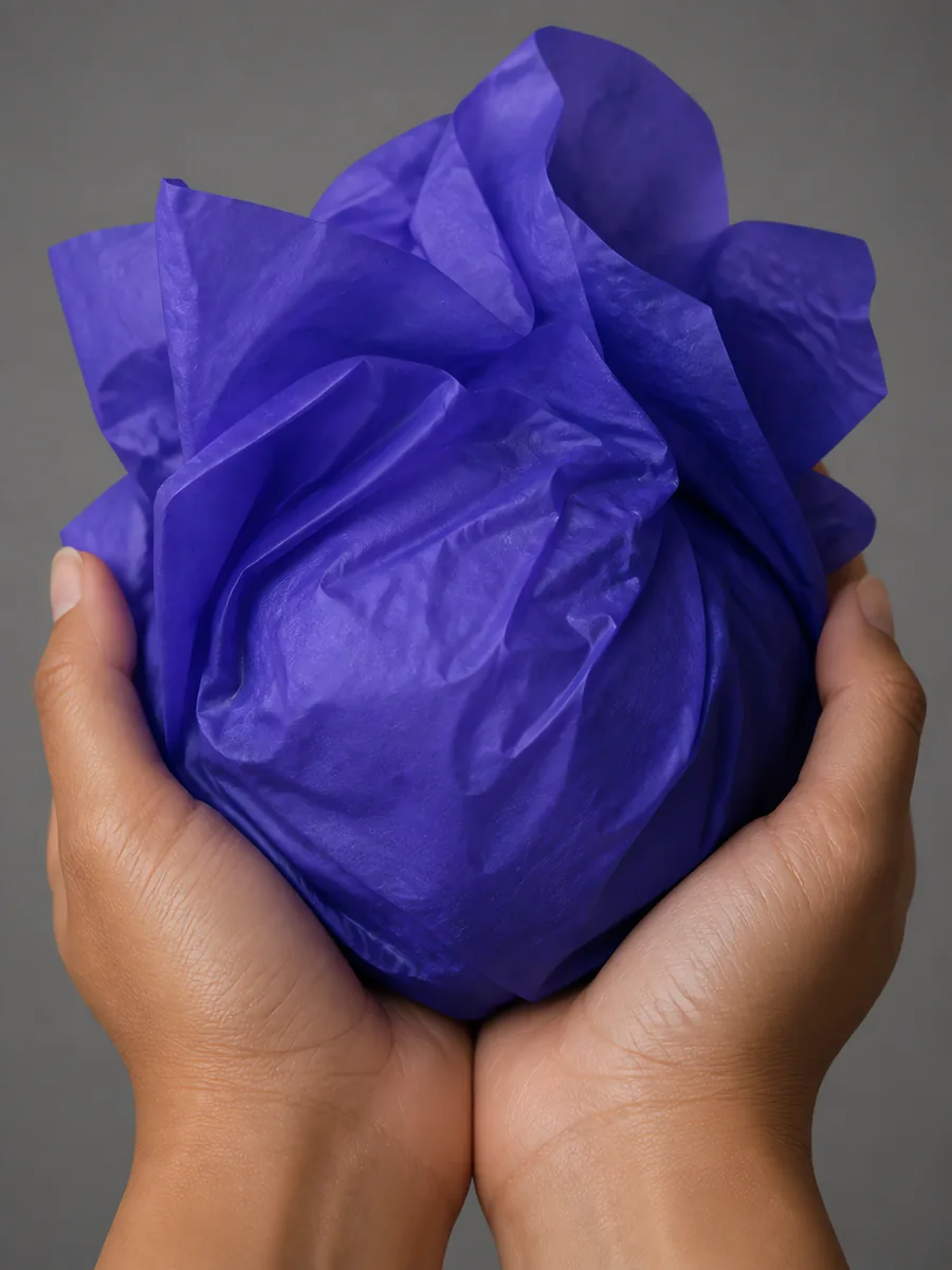 Manos sosteniendo desde abajo un envoltorio de papel seda azul cósmico