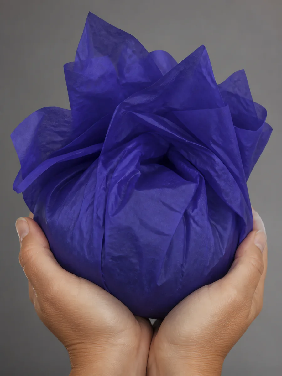 Manos sosteniendo desde abajo un envoltorio de papel seda azul grisáceo