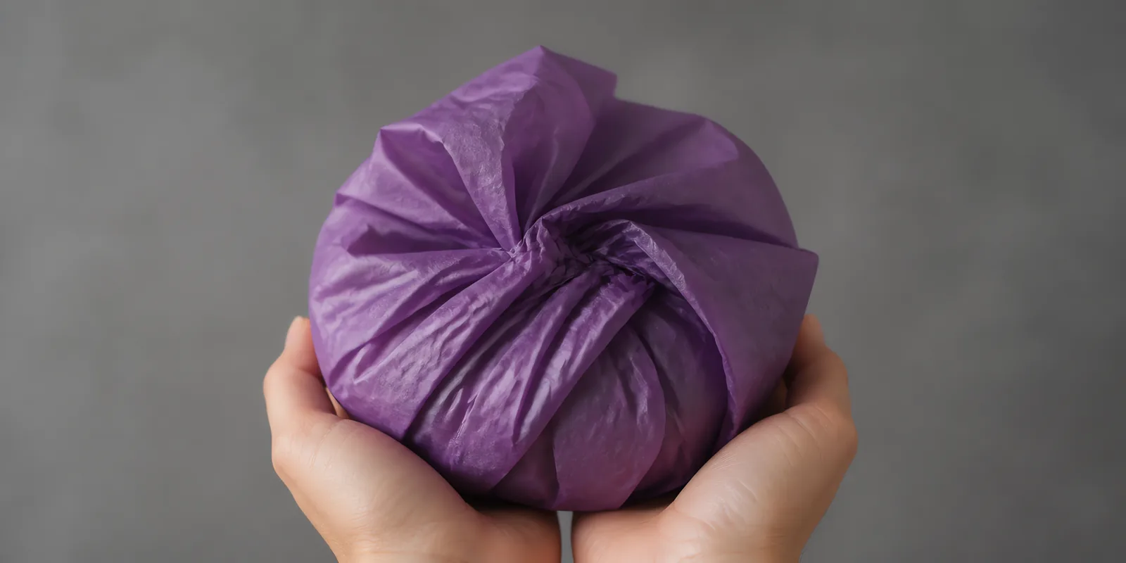 Manos sosteniendo desde abajo un envoltorio de papel seda ultravioleta