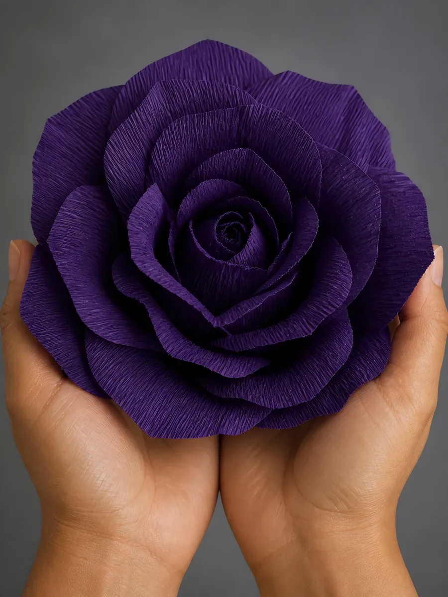 Manos sosteniendo una flor grande de papel crepé ultravioleta
