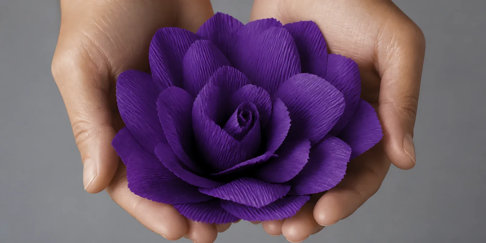 Manos sosteniendo una flor grande de papel crepé violeta eléctrico