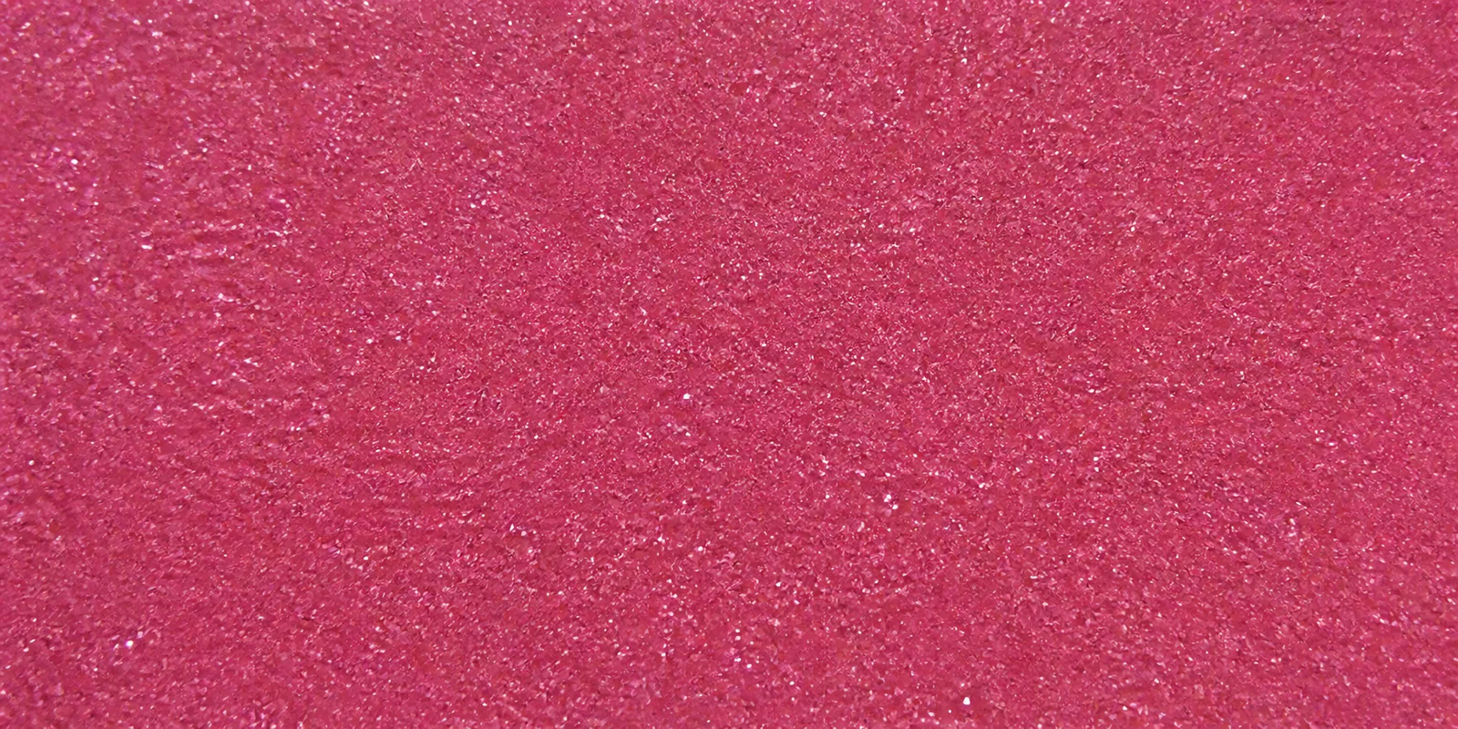 Macro del papel con glitter fucsia princesa, con las partículas separadas brillando sobre la hoja