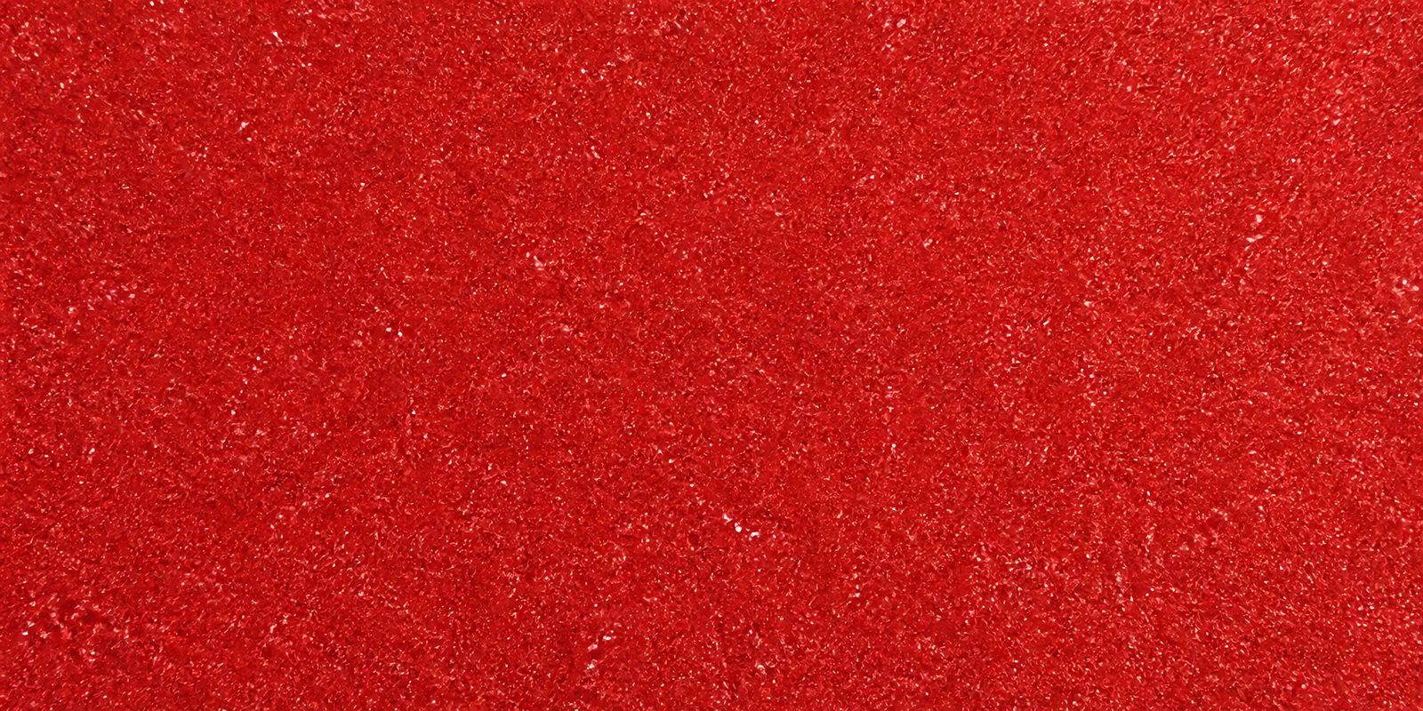 Macro del papel con glitter rojo manzana encantada, con las partículas separadas brillando sobre la hoja