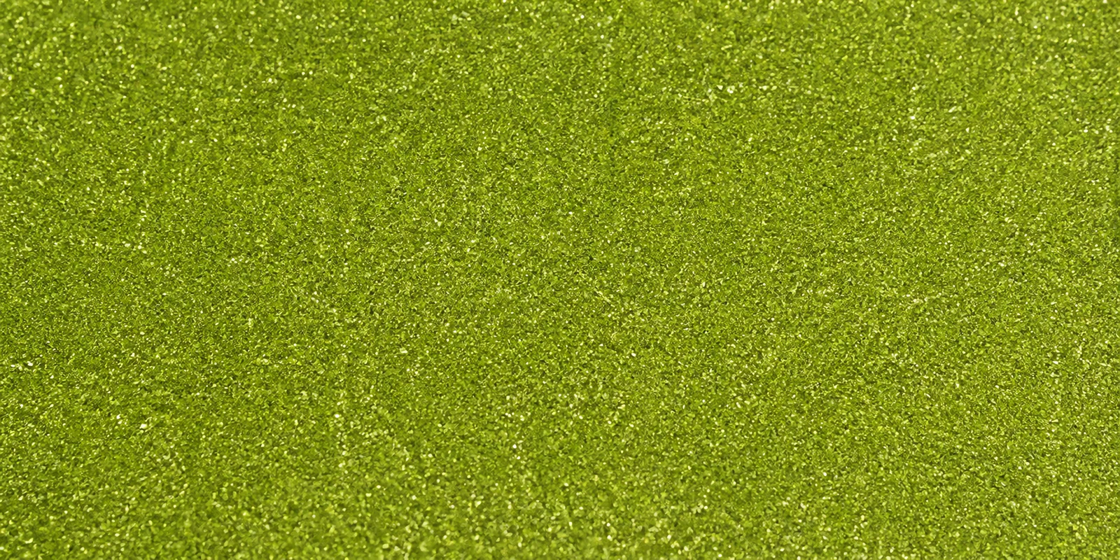 Macro del papel con glitter verde trebol de la suerte, con las partículas separadas brillando sobre la hoja