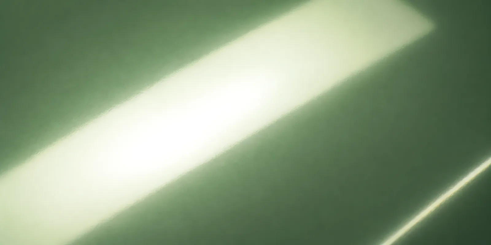 Superficie del papel metalizado Metalina, con el reflejo corriendo sobre la hoja, en el acabado verde palta