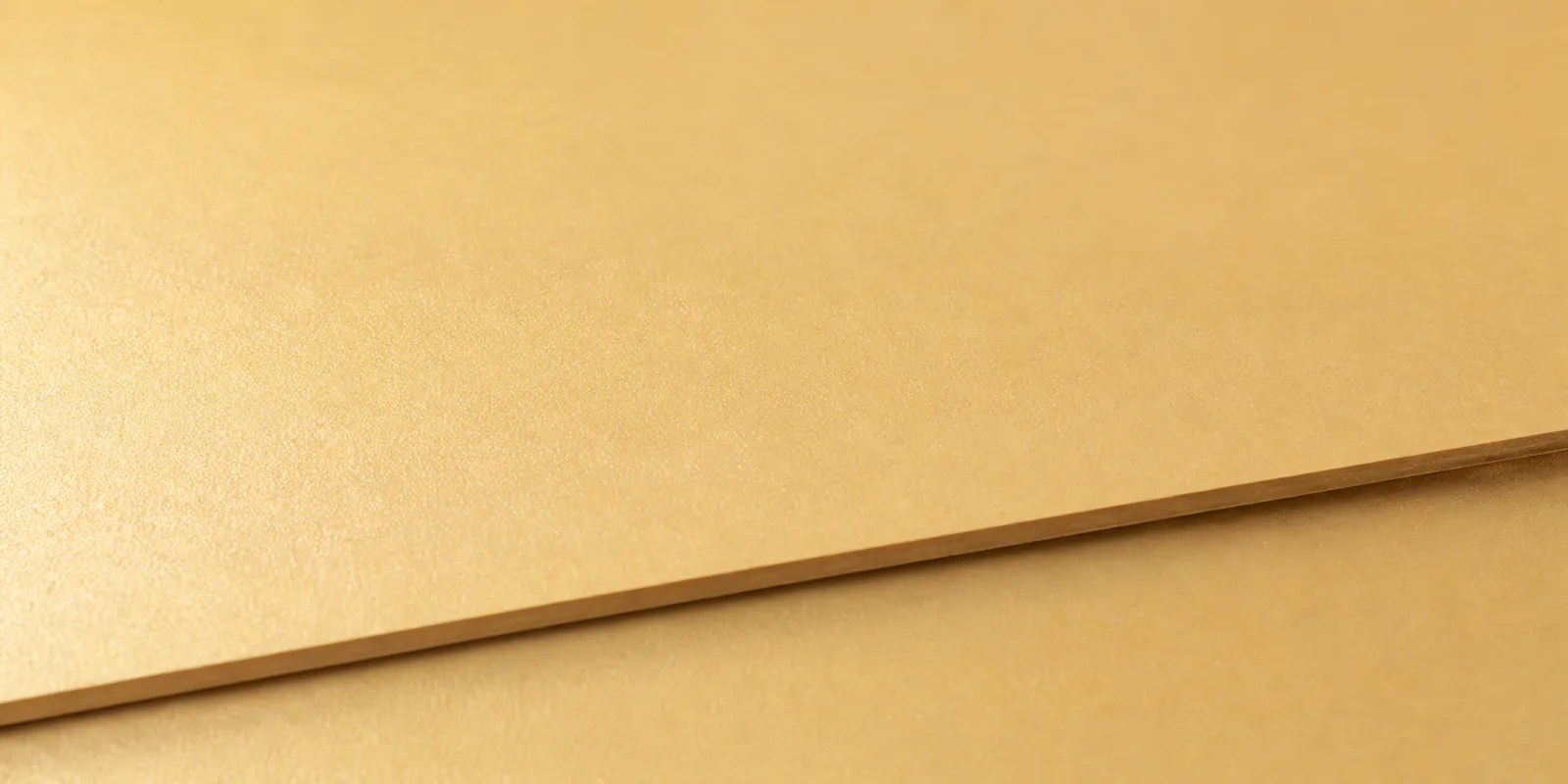 Detalle del papel perlado dorado, con el satinado corriendo sobre la hoja