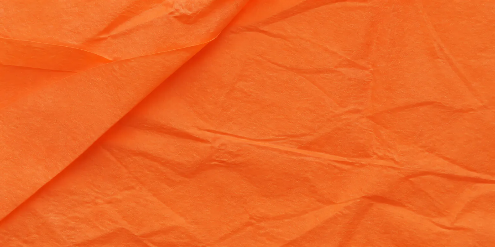 Textura del papel seda naranja, con sus arrugas finas y sus pliegues