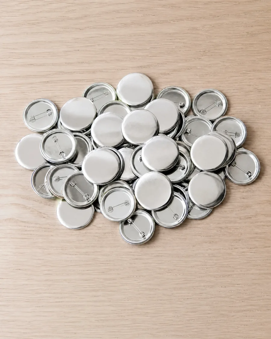 Pins metálicos de 32 mm sobre la mesa, con un pin terminado al lado