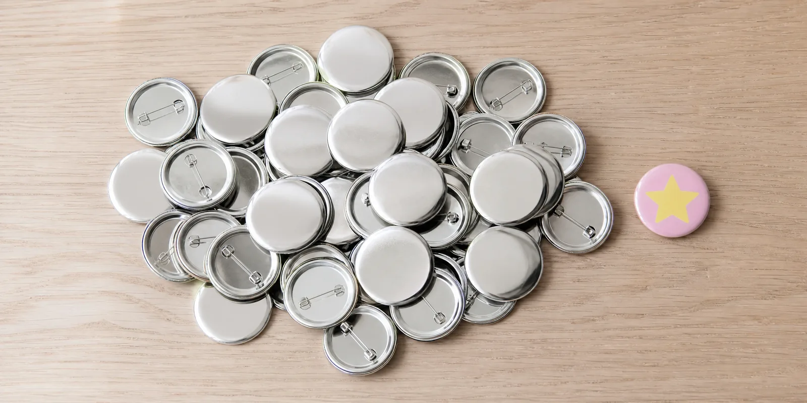 Pins metálicos de 32 mm sobre la mesa, con un pin terminado al lado