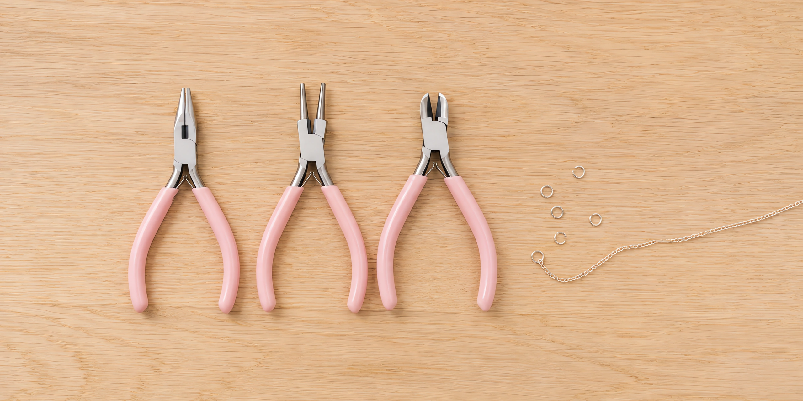 Las tres pinzas del set de joyería sobre la mesa, con una argolla cerrada al lado