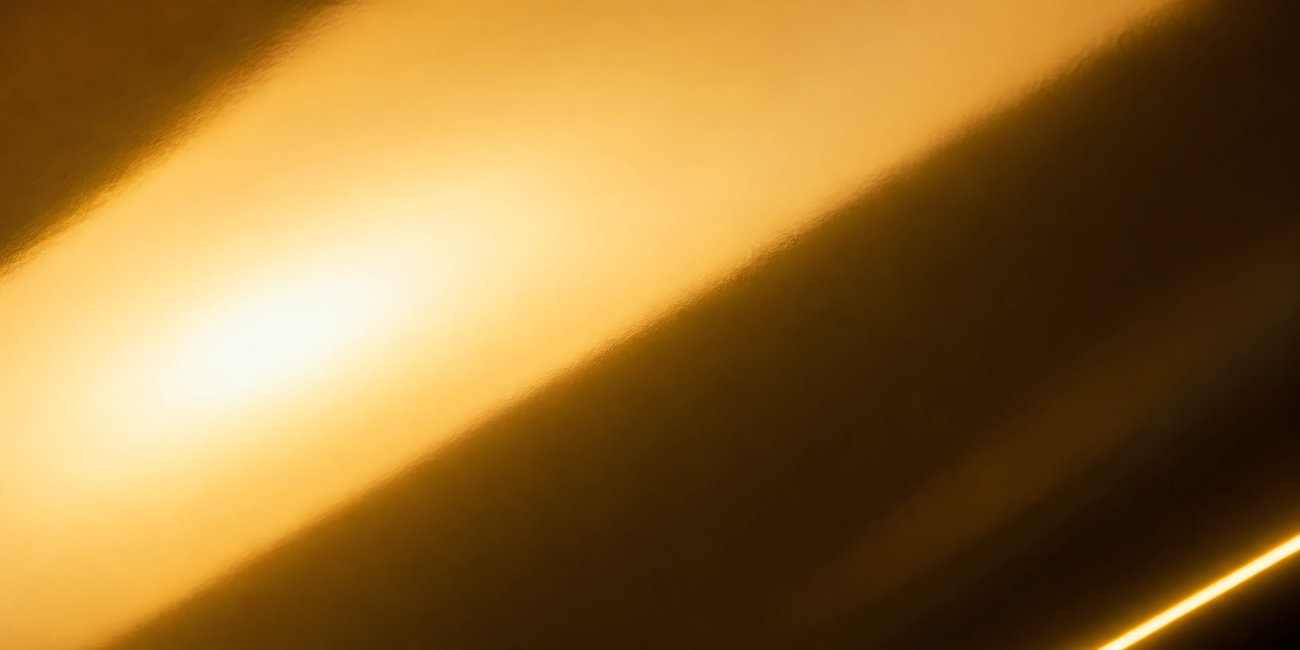 Superficie del papel metalizado Metalina, con el reflejo corriendo sobre la hoja, en el acabado dorado chita