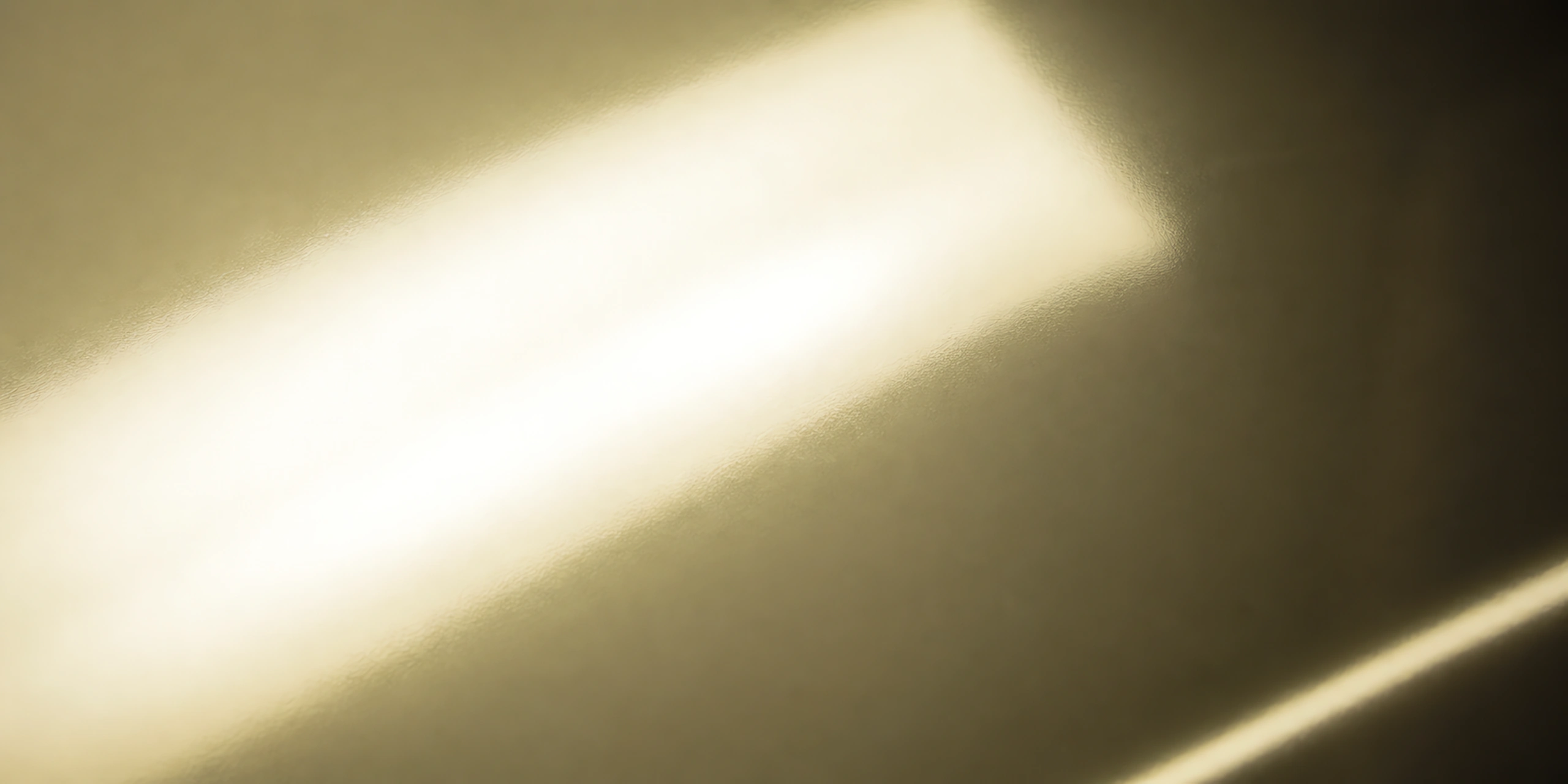 Superficie del papel metalizado Metalina, con el reflejo corriendo sobre la hoja, en el acabado dorado claro