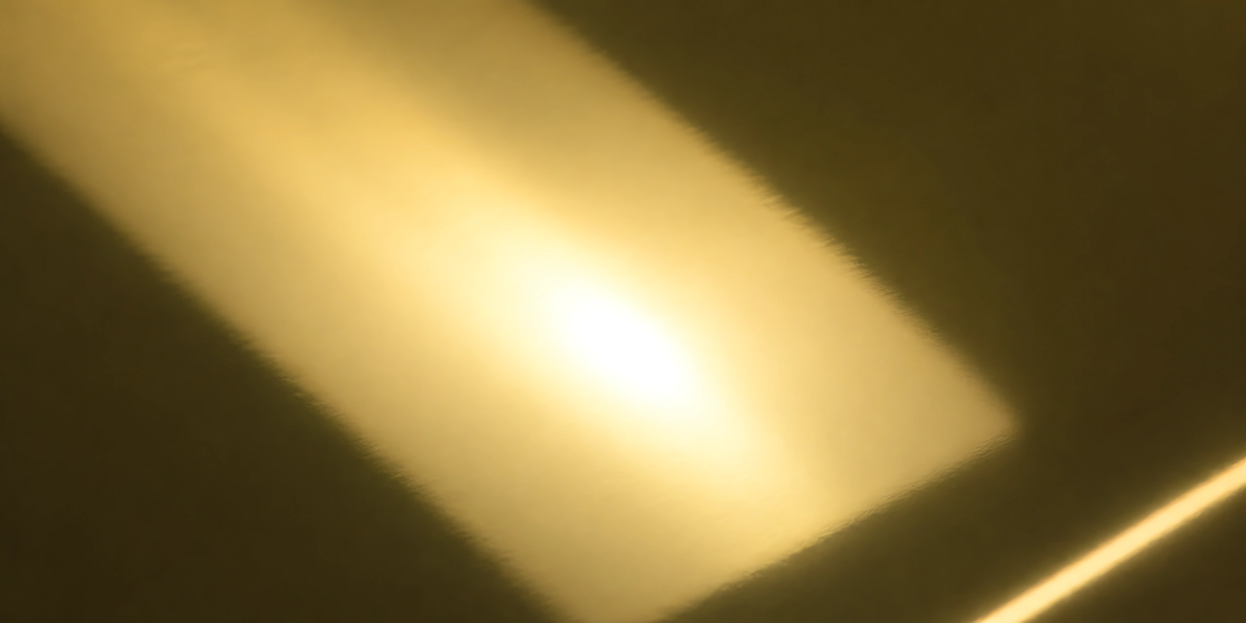 Superficie del papel metalizado Metalina, con el reflejo corriendo sobre la hoja, en el acabado oro moneda