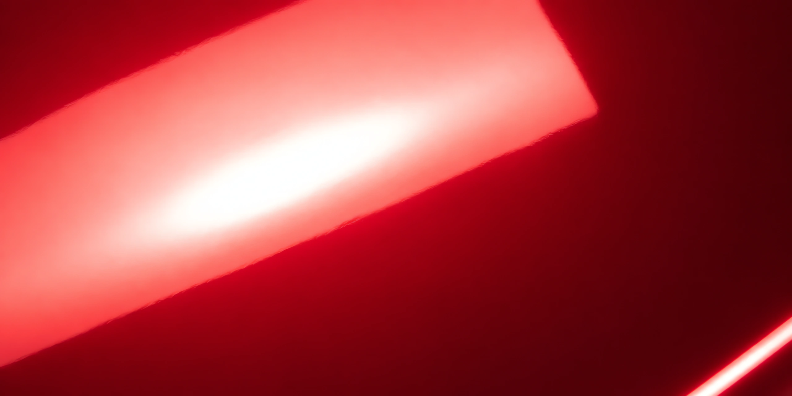 Superficie del papel metalizado Metalina, con el reflejo corriendo sobre la hoja, en el acabado rojo navidad