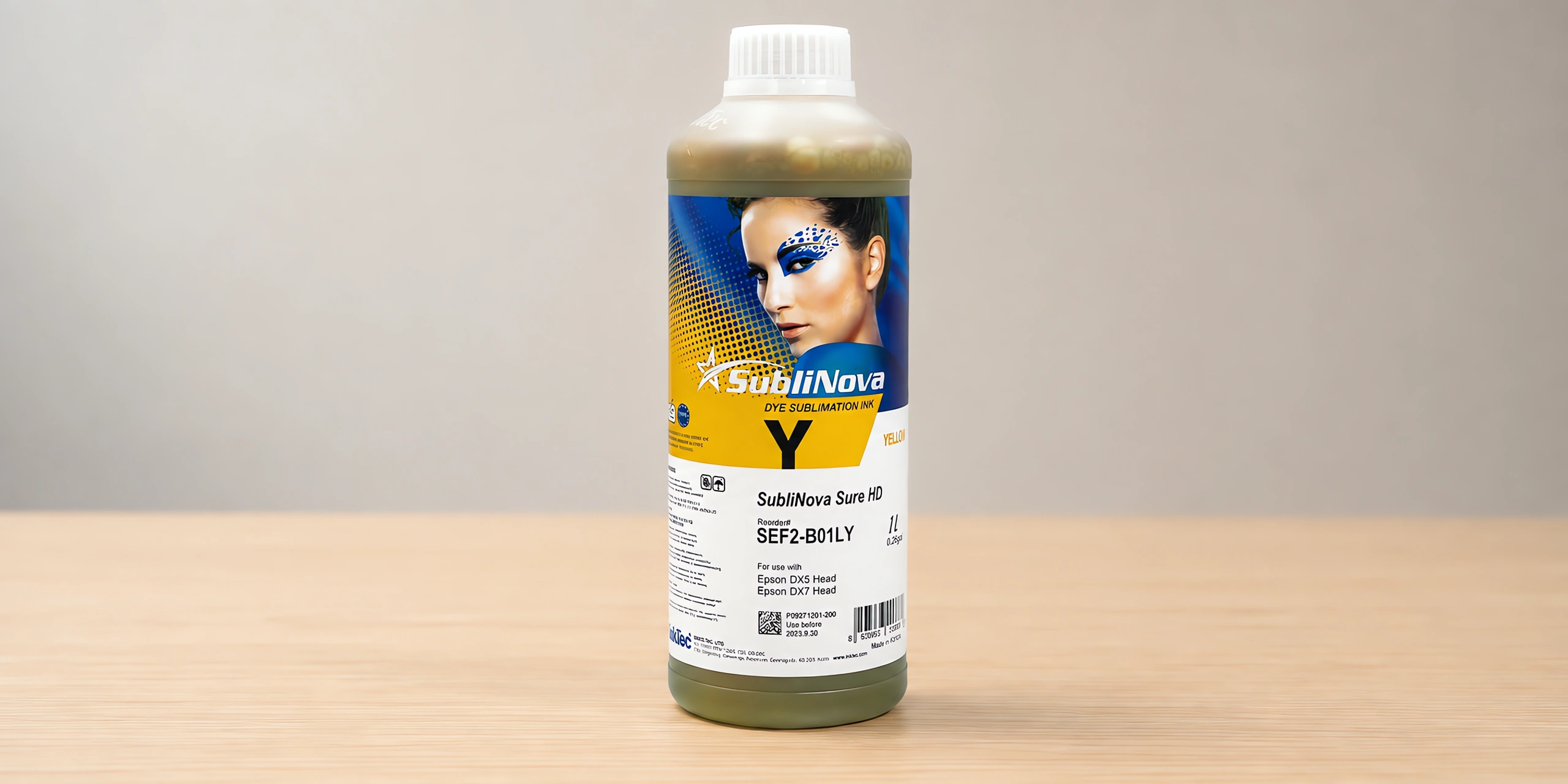 Tinta para sublimar de gran formato en su envase amarillo, sobre la mesa de trabajo