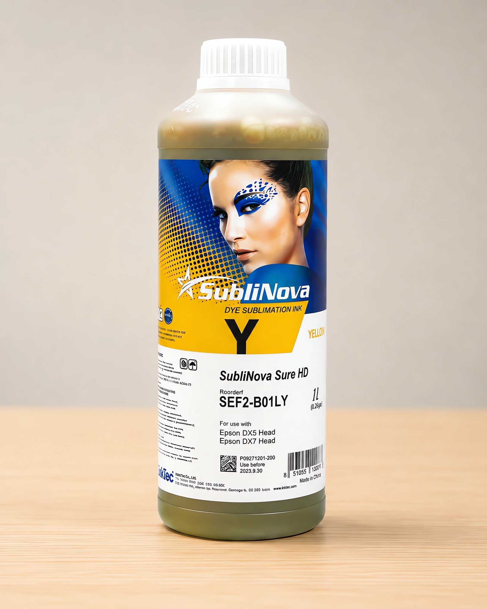 Tinta para sublimar de gran formato en su envase amarillo, sobre la mesa de trabajo