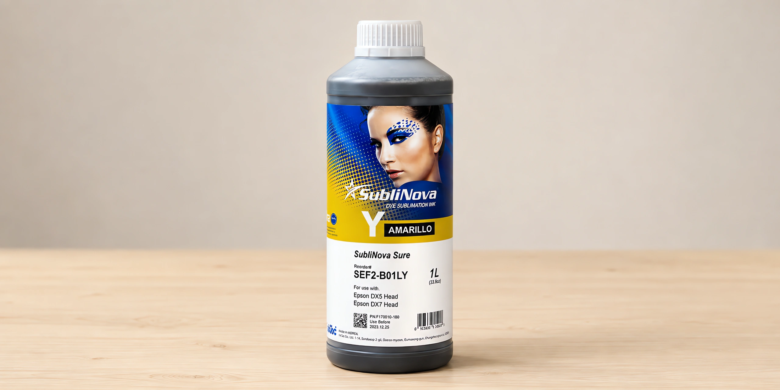 Tinta para sublimar de gran formato en su envase amarillo, sobre la mesa de trabajo