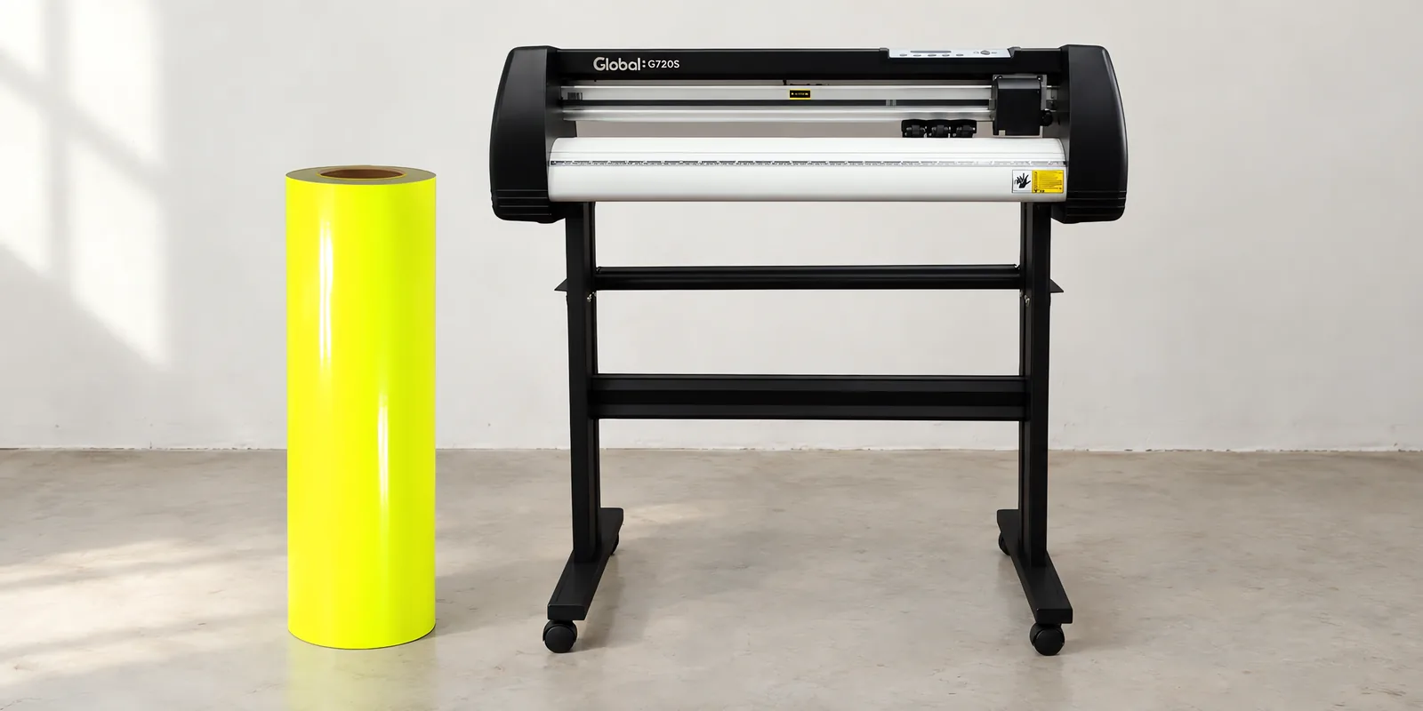 Rollo de vinilo de corte fluo, parado junto al plóter de corte