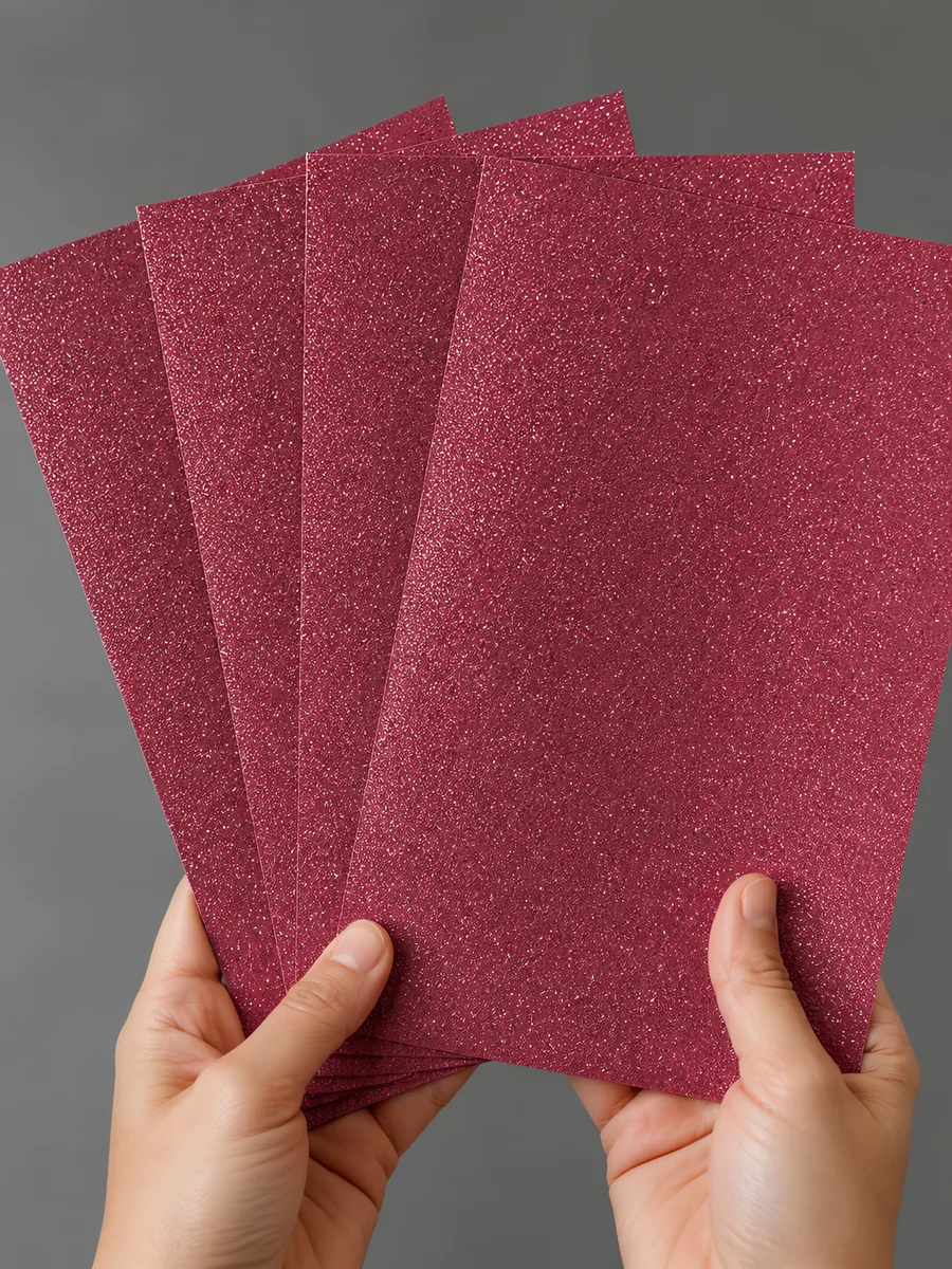 Manos sosteniendo varias hojas de papel con glitter violeta valle de fantasia abiertas en abanico