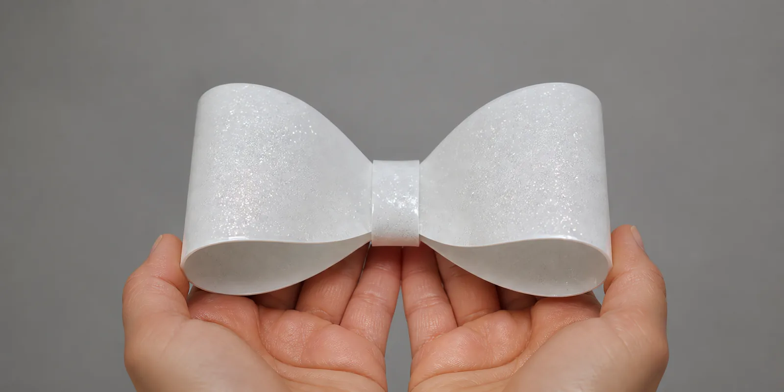 Manos sosteniendo un moño de papel blanco con glitter