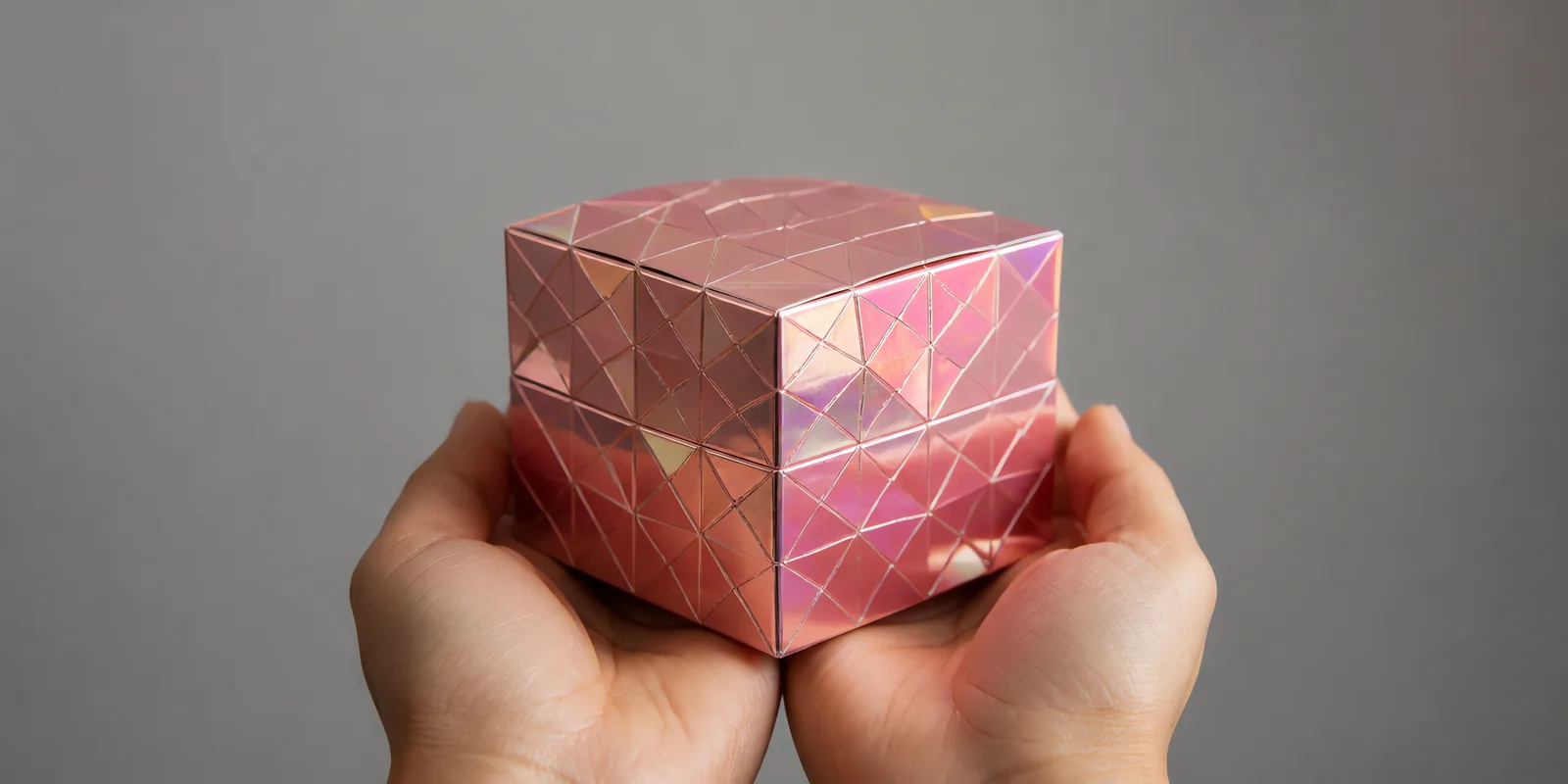 Manos sosteniendo una cajita armada con una hoja de Metalina en el acabado diamante rosa