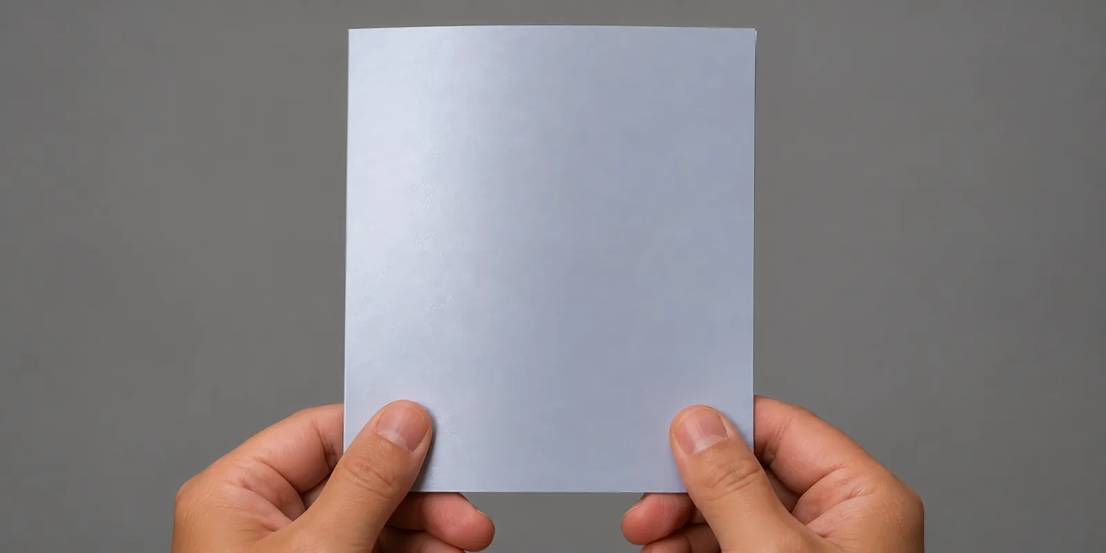 Manos sosteniendo una tarjeta doblada en papel perlado blanco