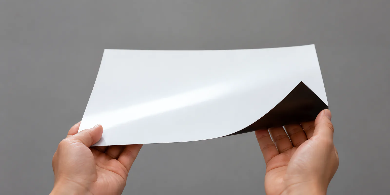 Manos sosteniendo una hoja de papel magnético con la esquina levantada