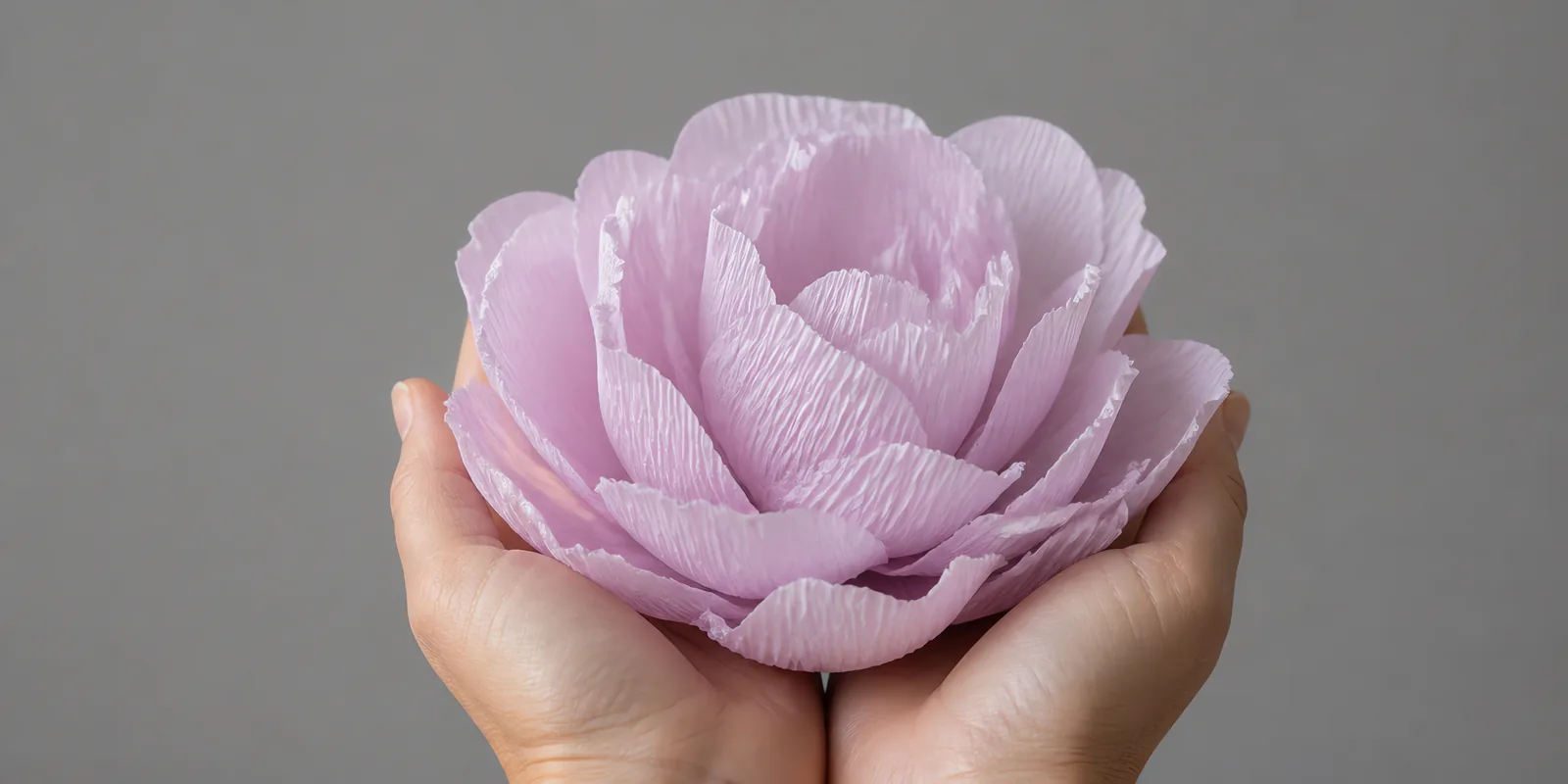 Manos sosteniendo una flor grande de papel crepé lavanda
