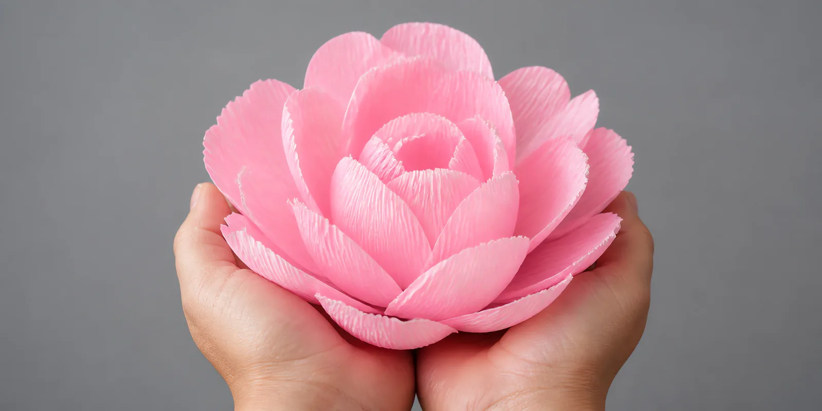 Manos sosteniendo una flor grande de papel crepé rosa chicle