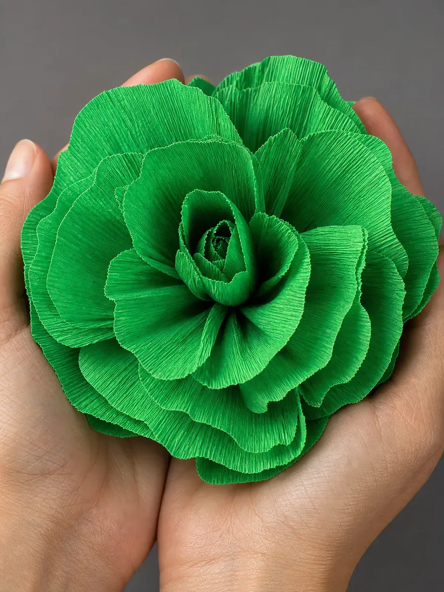Manos sosteniendo una flor grande de papel crepé verde manzana