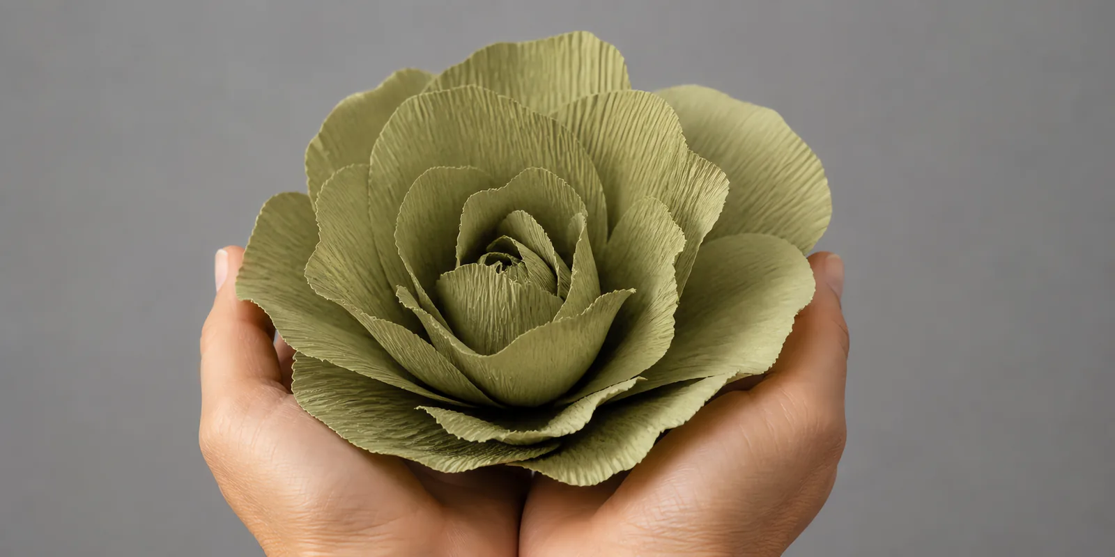Manos sosteniendo una flor grande de papel crepé verde selva