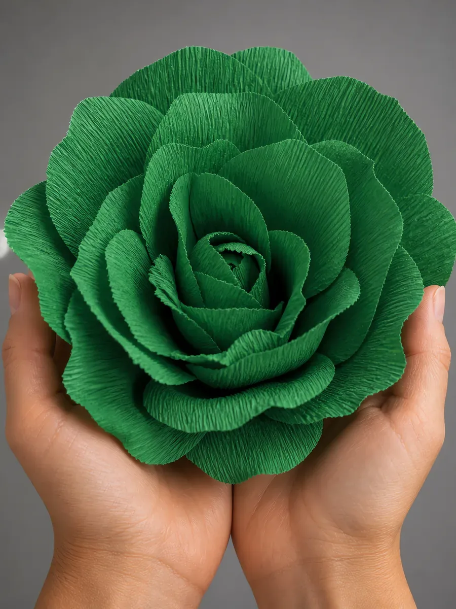 Manos sosteniendo una flor grande de papel crepé verde