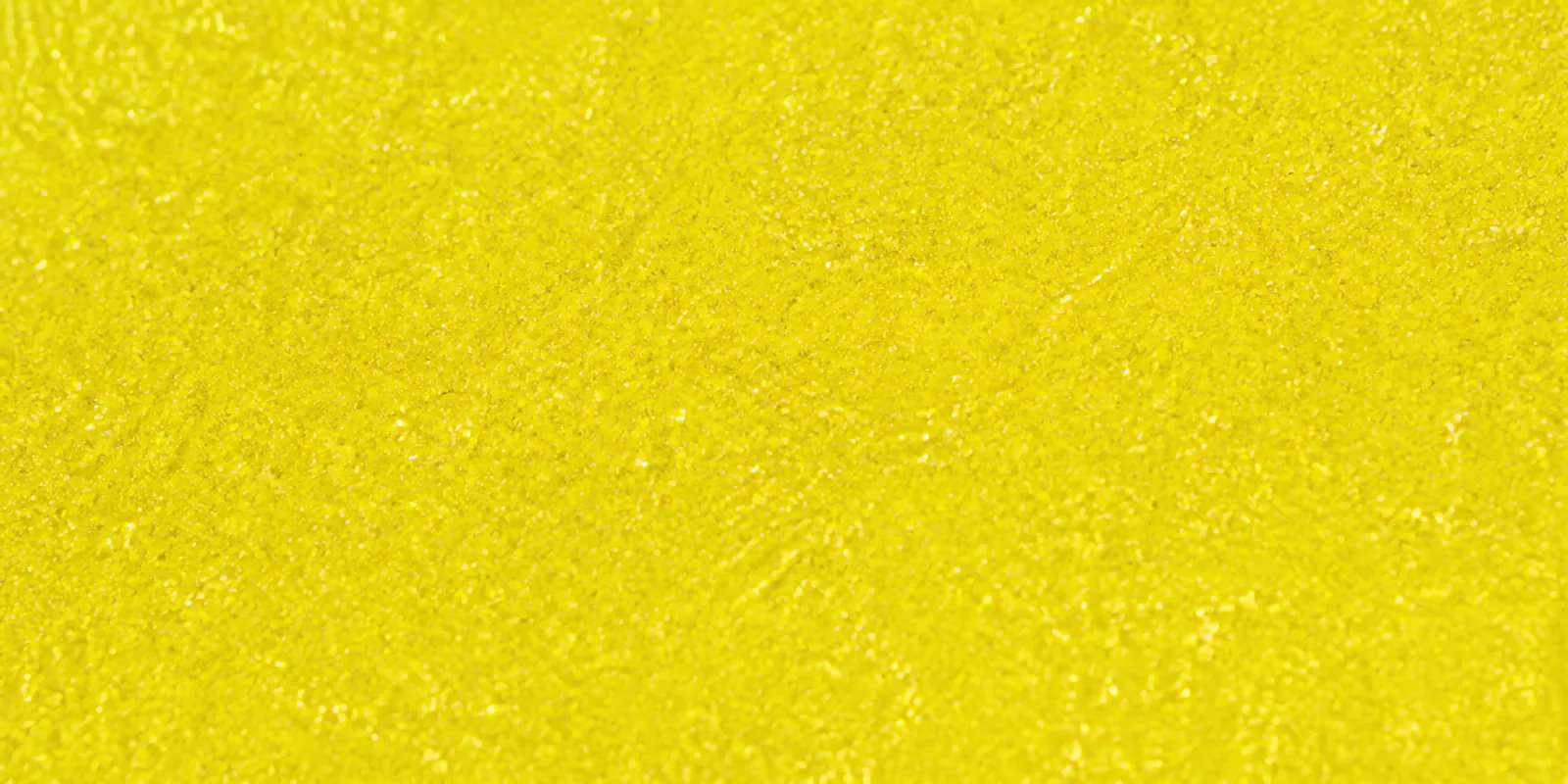 Macro del papel con glitter amarillo del tesoro, con las partículas separadas brillando sobre la hoja