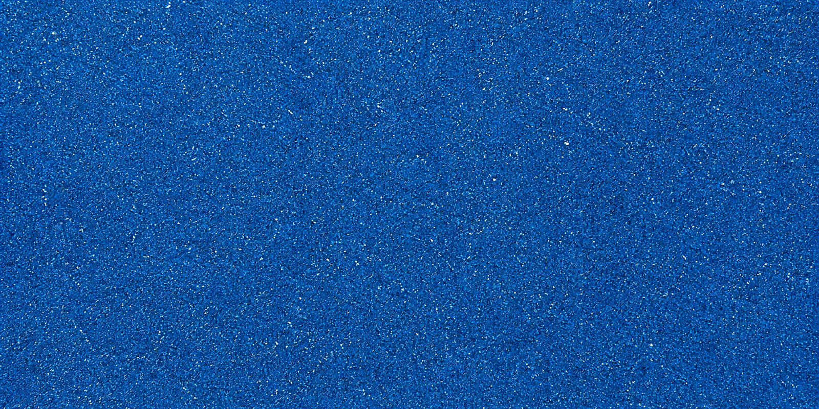 Macro del papel con glitter azul magia, con las partículas separadas brillando sobre la hoja