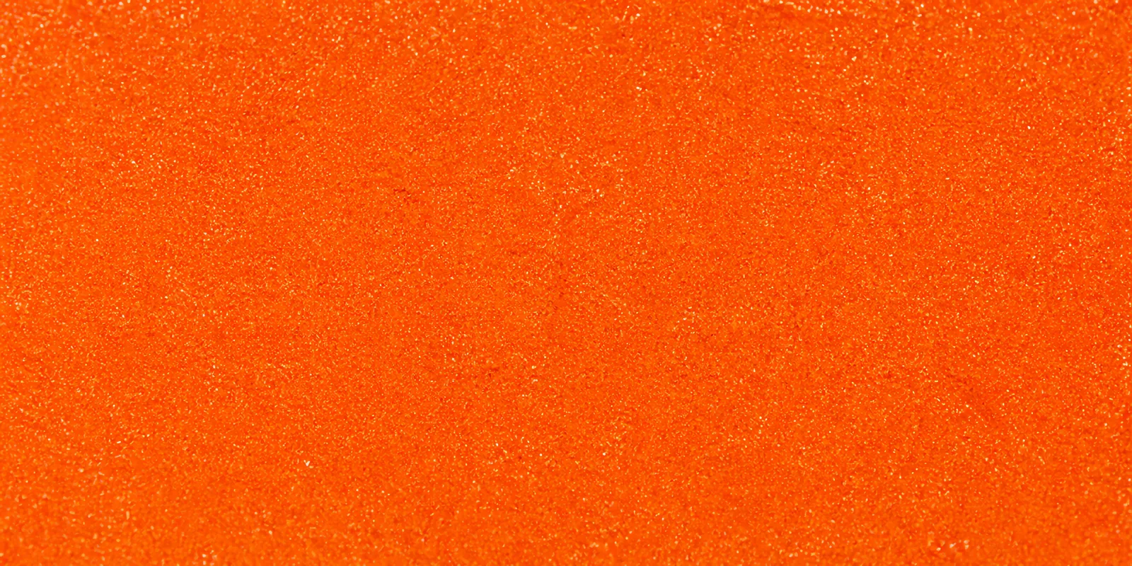 Macro del papel con glitter naranja soleado, con las partículas separadas brillando sobre la hoja