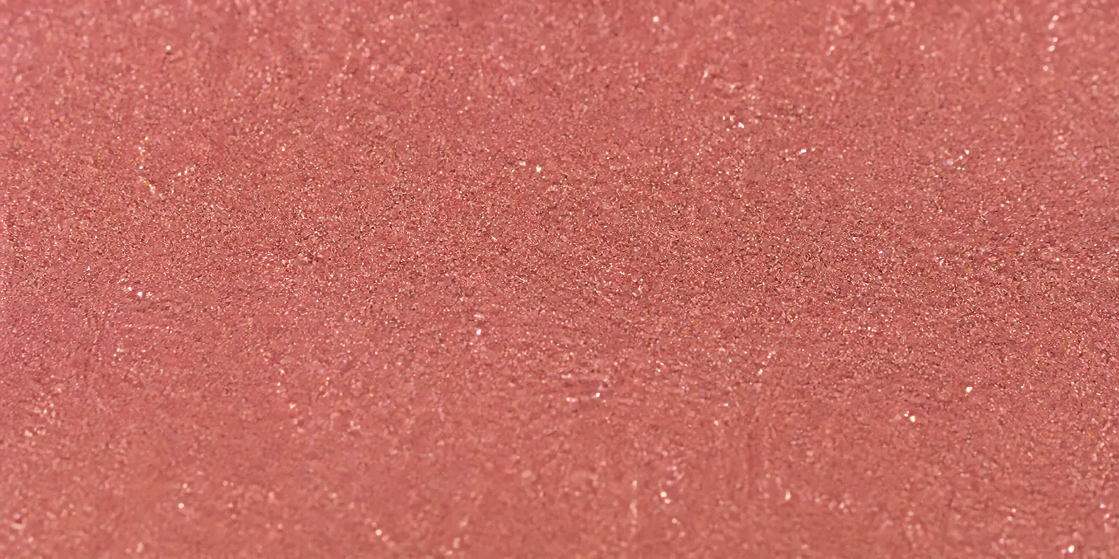 Macro del papel con glitter rosa gardenia, con las partículas separadas brillando sobre la hoja