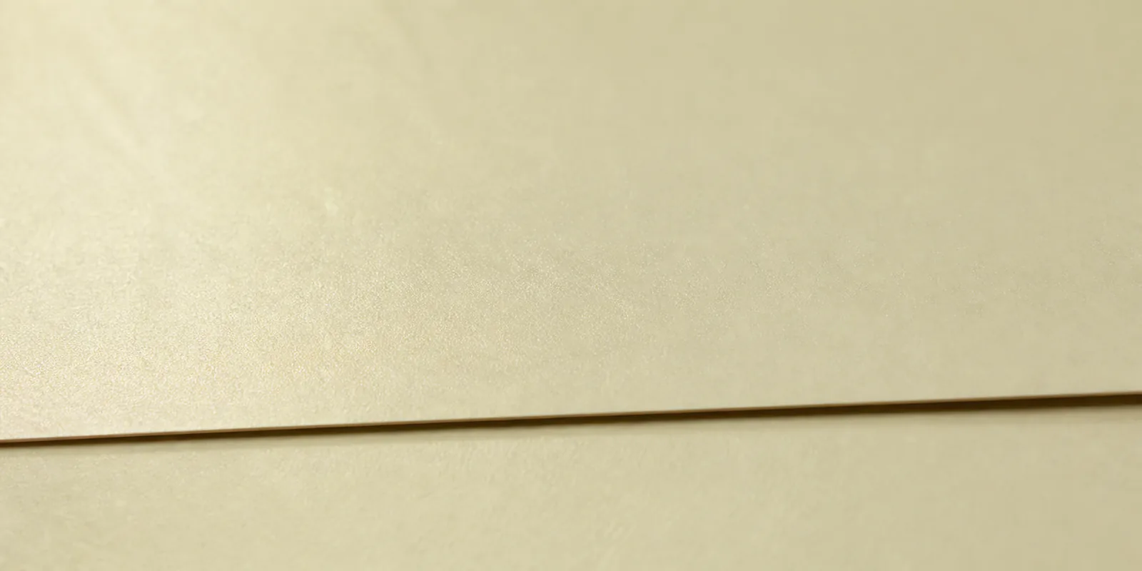 Detalle del papel perlado crema, con el satinado corriendo sobre la hoja