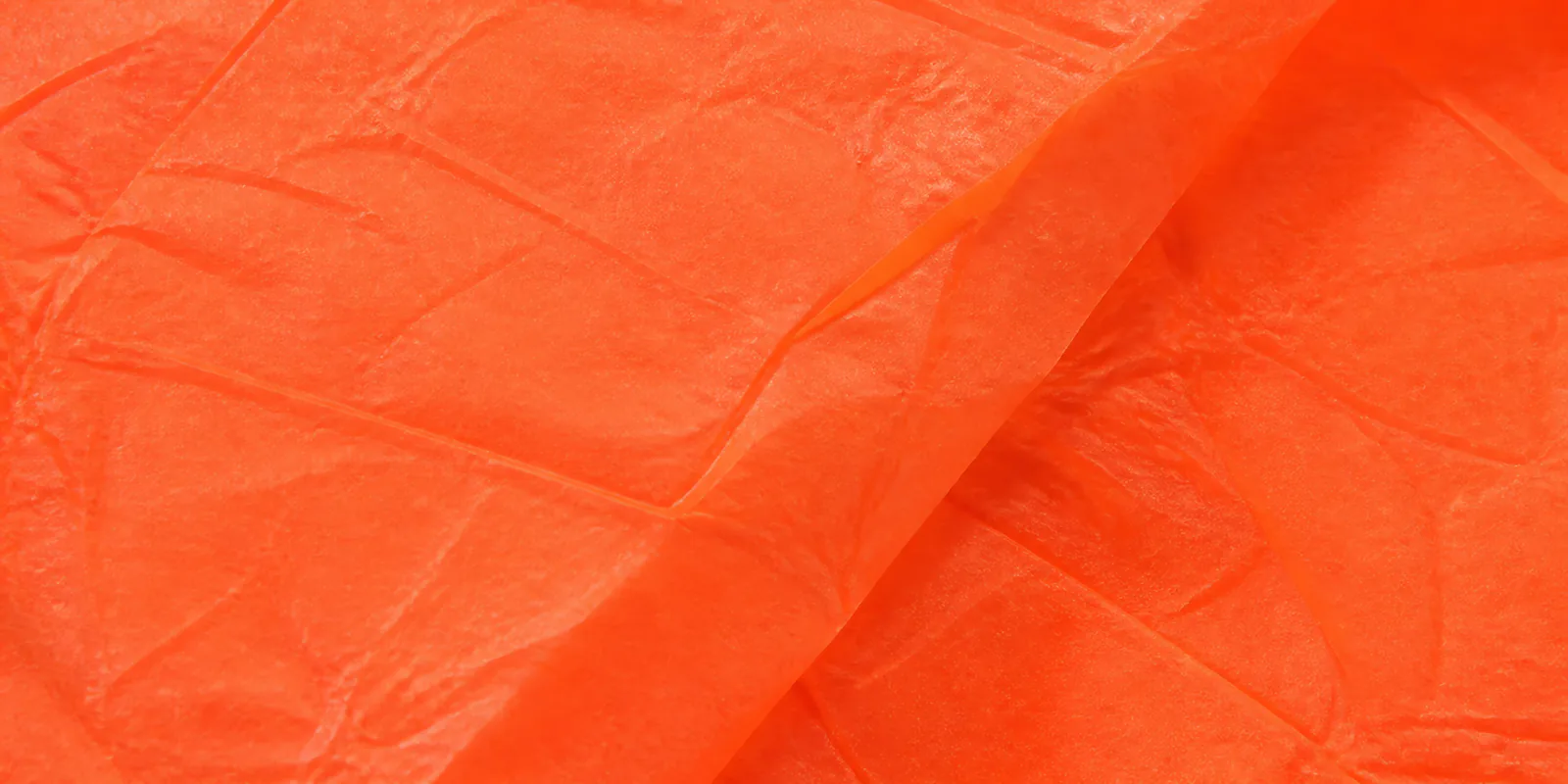 Textura del papel seda naranja fluor, con sus arrugas finas y sus pliegues