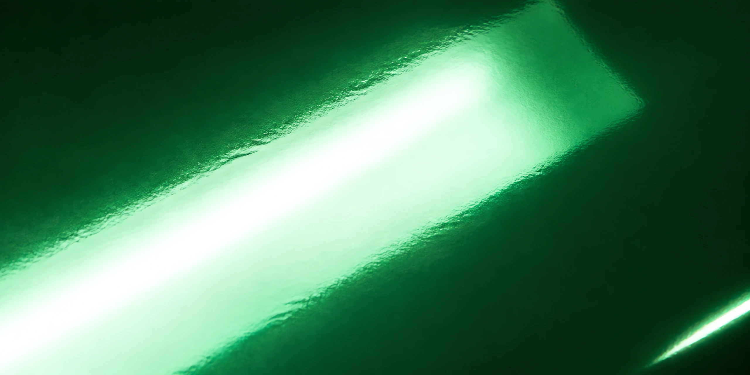 Superficie del papel metalizado Metalina, con el reflejo corriendo sobre la hoja, en el acabado verde pistacho