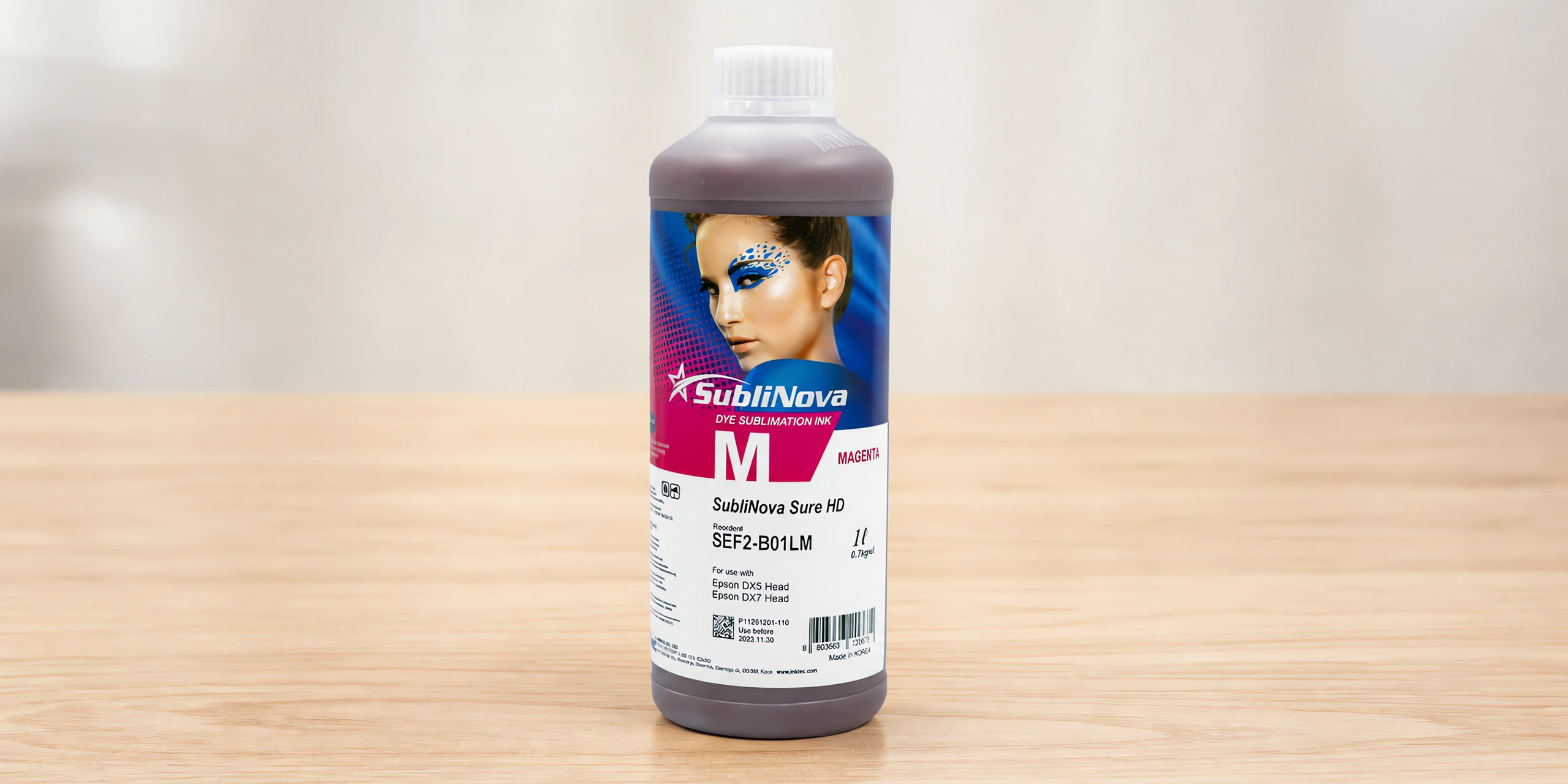 Tinta para sublimar de gran formato en su envase magenta, sobre la mesa de trabajo